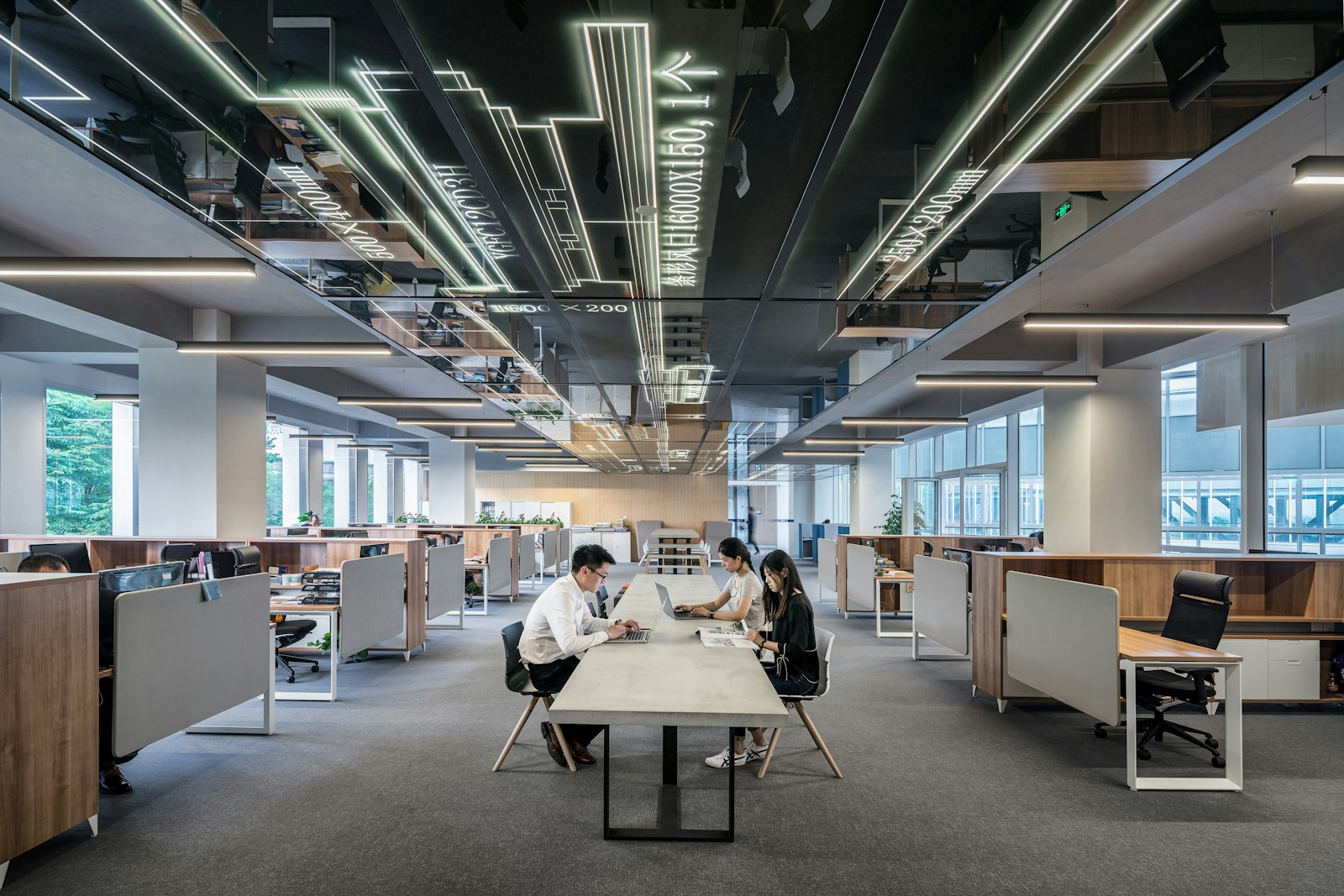 Three colleagues collaborating at a desk in a bright open-plan office