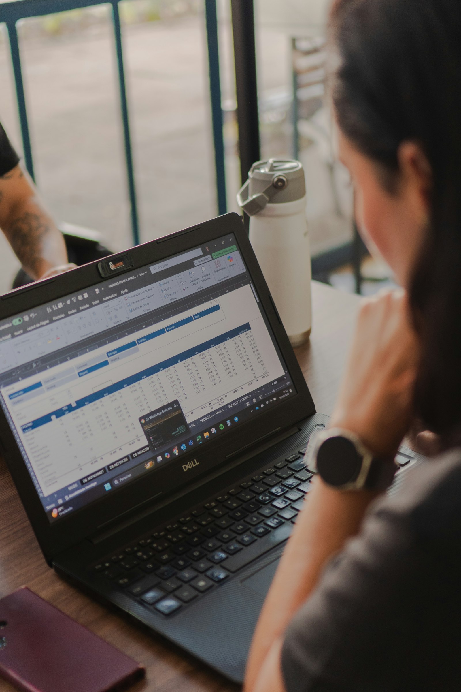 Woman working on a laptop showing spreadsheet data